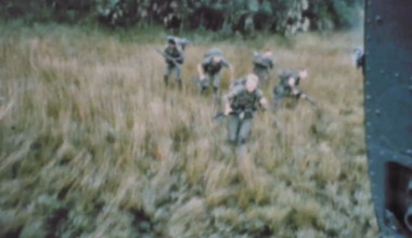 Huey door gunner sweeps the treeline with his M60 as what appears to be a Long-range reconnaissance patrol is evacuated in Vietnam
