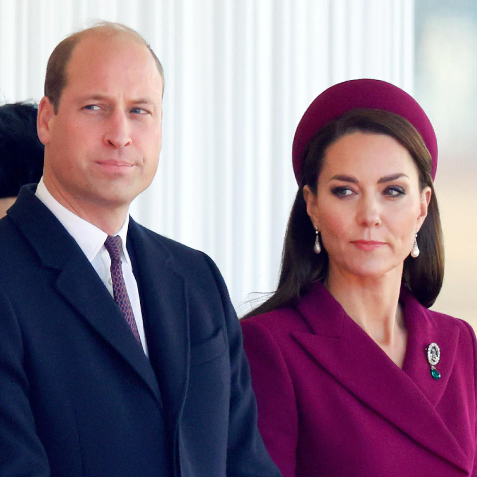 Prince William wears a suit and Kate Middleton wears a burgundy coat with matching hat.
