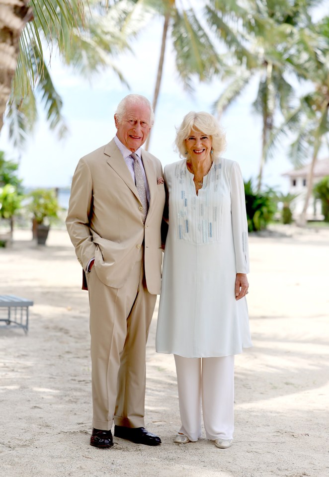 King Charles III and Queen Camilla smiling on a beach in Samoa.