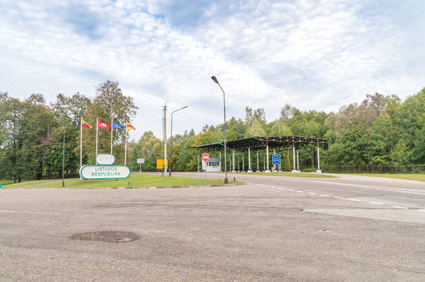 Border checkpoint at the entrance to Lithuania with flags, a “Lietuvos Respublika” sign, and a covered inspection area.