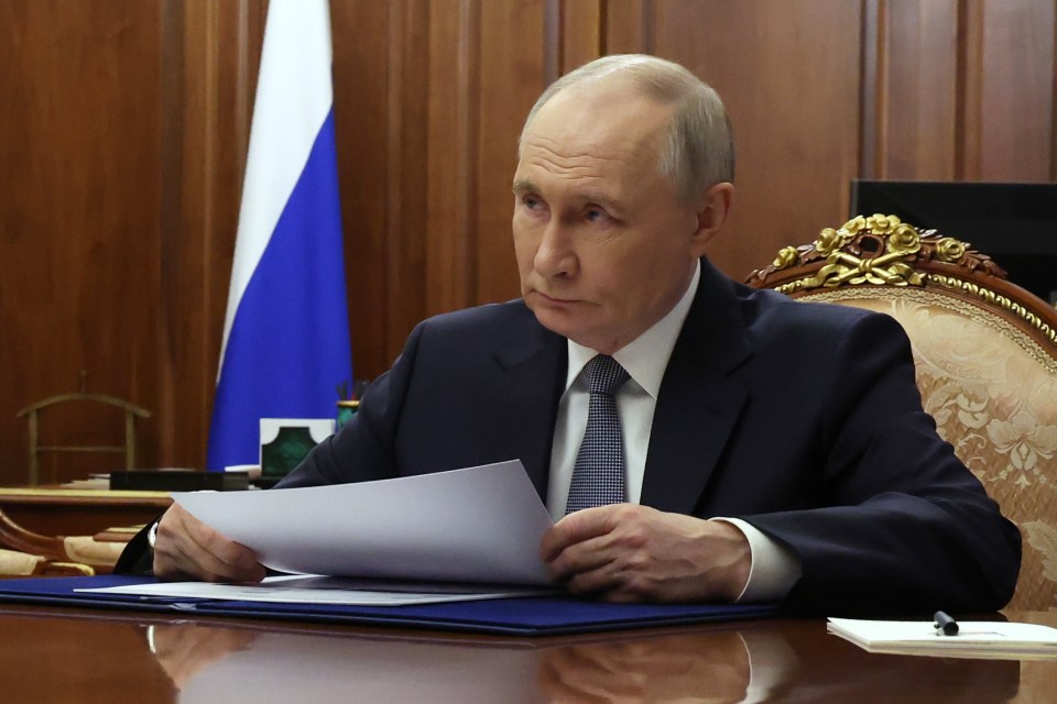 Vladimir Putin reviewing documents at a meeting.