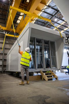 A worker stands in front of a module in a factory produced prefabricated housing