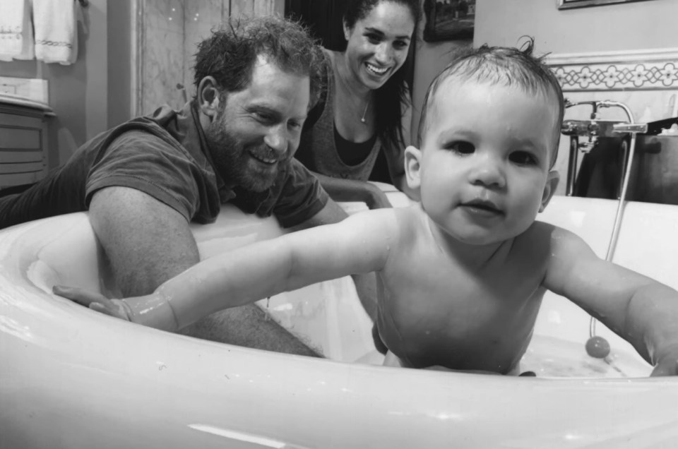 Black and white photo of Prince Harry, Meghan Markle, and their baby in a bathtub.