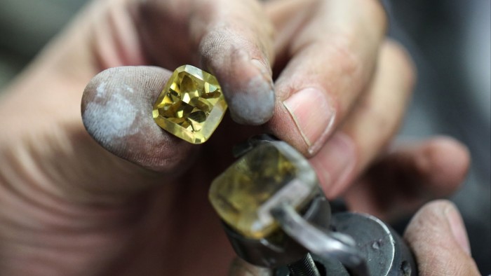 A worker holds a cut diamond in the manual polishing unit at the Antwerp World Diamond Center in Antwerp, Belgium