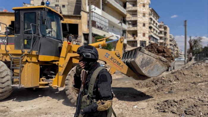 A fighter stands near ongoing roadworks in Aleppo, Syria