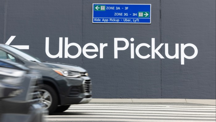 Vehicles pass signs pointing toward an Uber pickup location at Washington Dulles International Airport