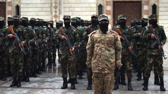 The soldiers are lined up and are wearing balaclavas and carrying rifles