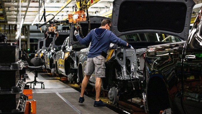 A worker is seen installing an engine in a vehicle at an assembly plant in Indiana