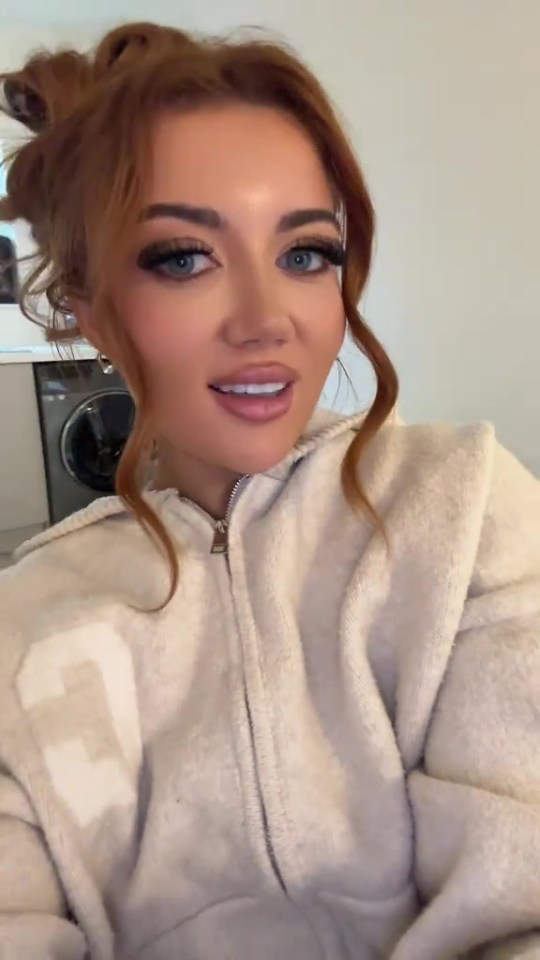 Woman in cream zip-up hoodie after £13,000 cosmetic surgery.