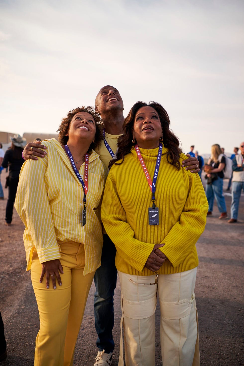 three individuals dressed in yellow attire standing outdoors with access badges