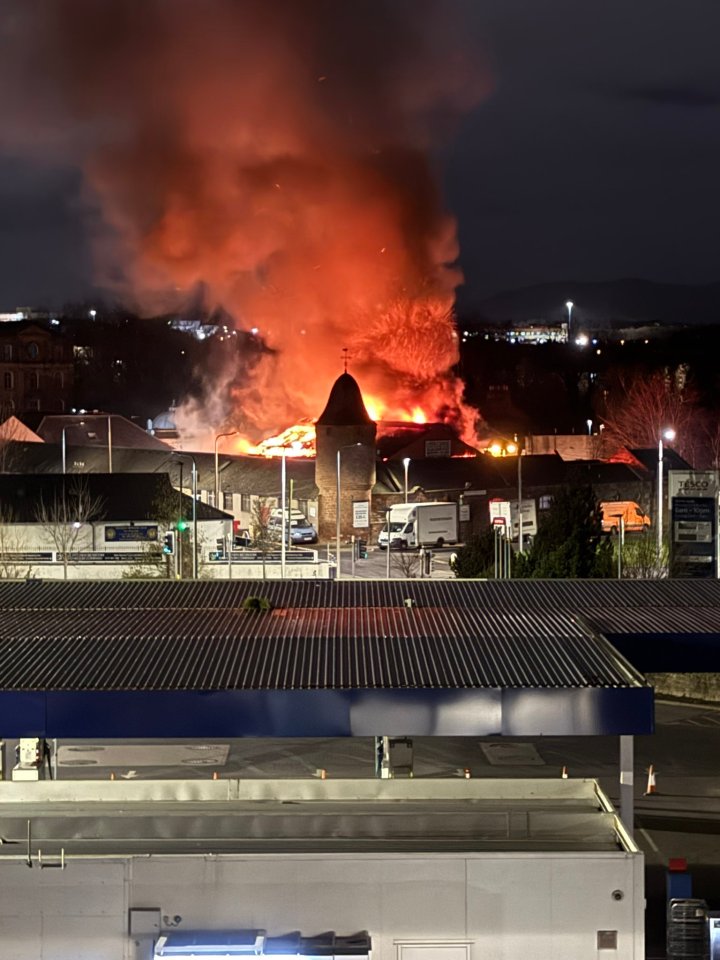 Photo of a large fire engulfing a warehouse at night.