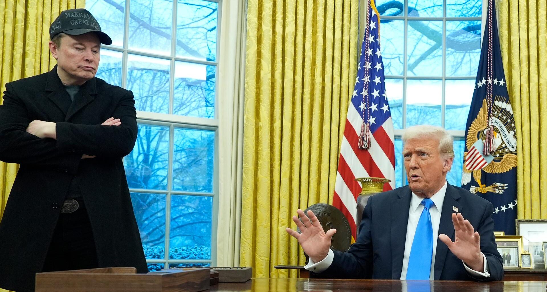 Präsident Donald Trump spricht mit Reportern im Oval Office während Elon Musk zuhört.