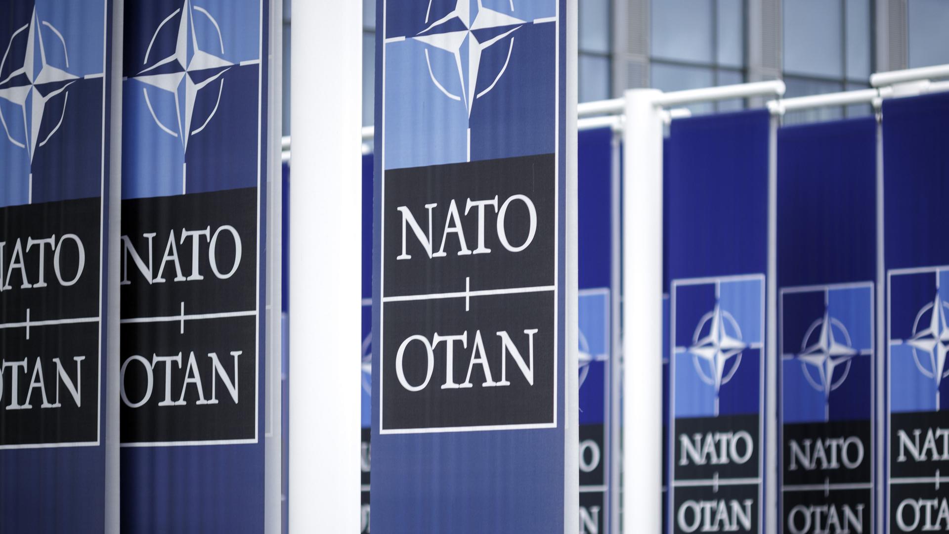 Mehrere Flaggen mit dem NATO-Logo hängen an einem Gebäude. Mehrere Flaggen mit dem NATO-Logo hängen an einem Gebäude.