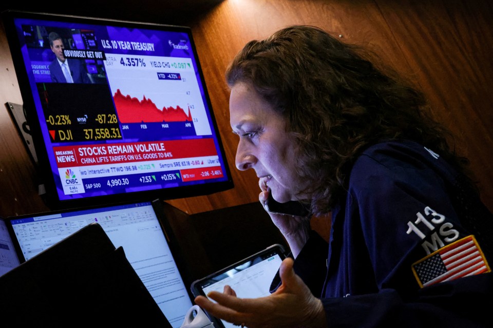 Trader at the New York Stock Exchange working on multiple screens displaying stock market data.