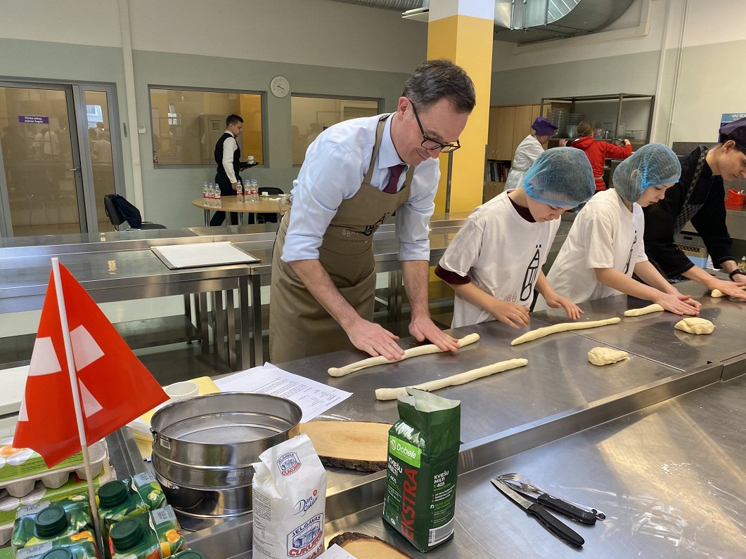 Swiss ambassador Martin Michelet rolls out dough for the Zopf