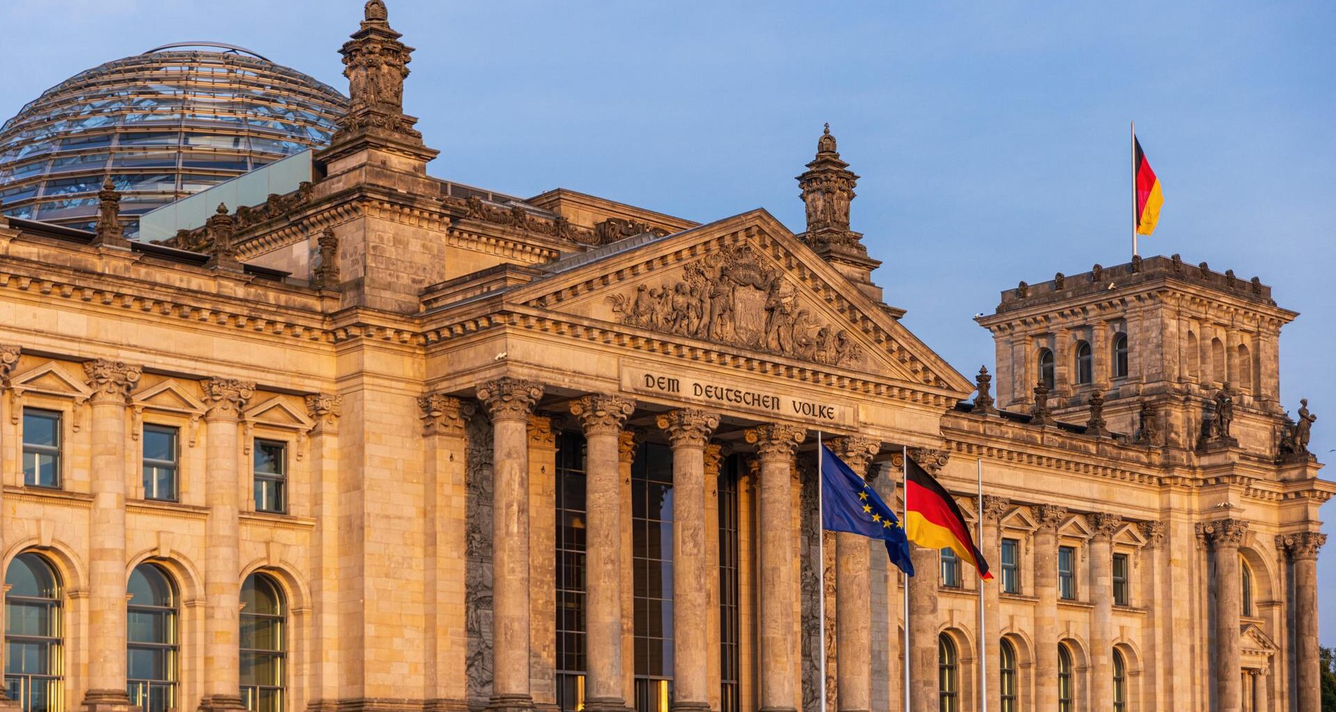 Die deutsche und die europäische Flagge wehen vor dem Reichstagsgebäude in Berlin.