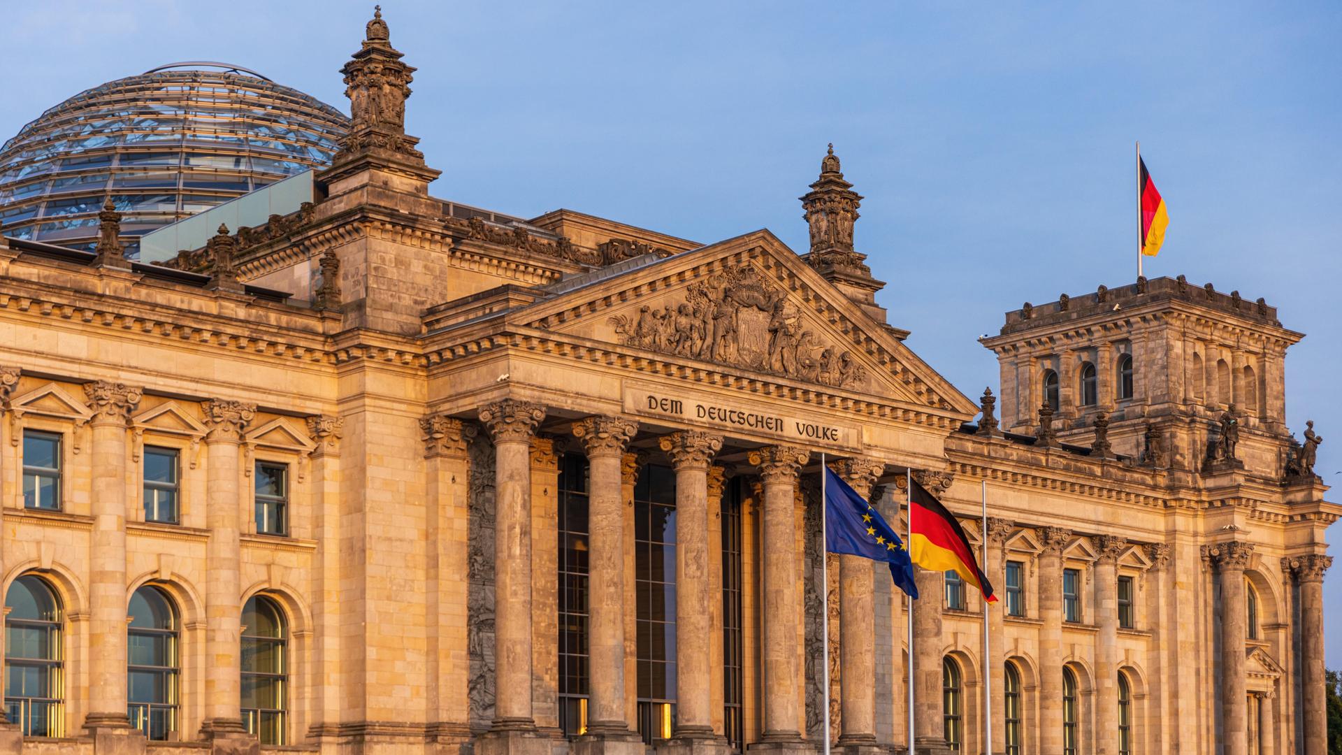 Die deutsche und die europäische Flagge wehen vor dem Reichstagsgebäude in Berlin.