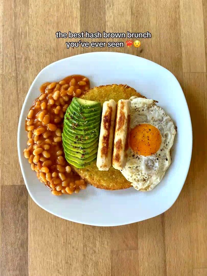 Hash brown brunch with baked beans, avocado, sausages, and fried egg.