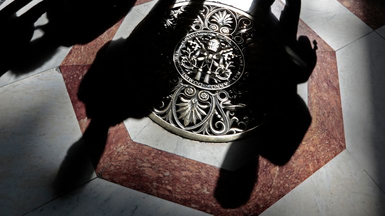 Shadows of tourists are cast across a papal crest dedicated to Pope Pius XII on the floor of Saint Peter's Basilica at the Vatican March 11, 2013. Roman Catholic Cardinals will begin a conclave on Tuesday to elect the Church's 266th pontiff and a successor to Pope Benedict, who abdicated unexpectedly last month. REUTERS/Eric Gaillard (VATICAN - Tags: RELIGION TRAVEL)
