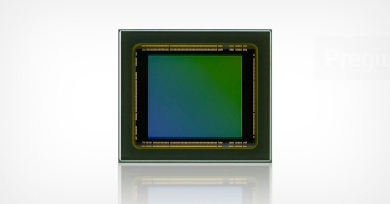 Close-up of a square electronic sensor chip with a green and blue gradient in the center, bordered by a metallic frame, set against a plain white background.