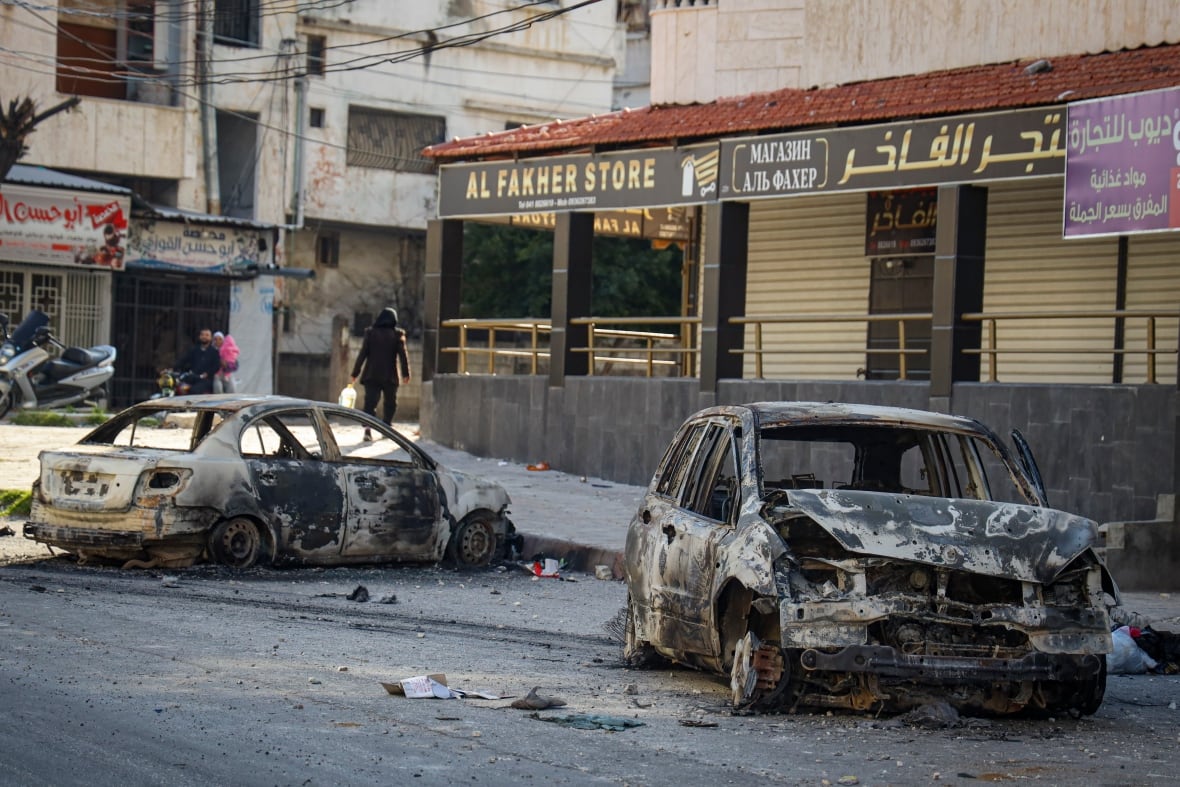 Burnt cars in the middle of a street.