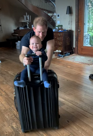 Prince Harry pushing his baby son on a suitcase.