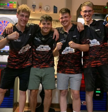 Four young men in bowling shirts pose for a photo.