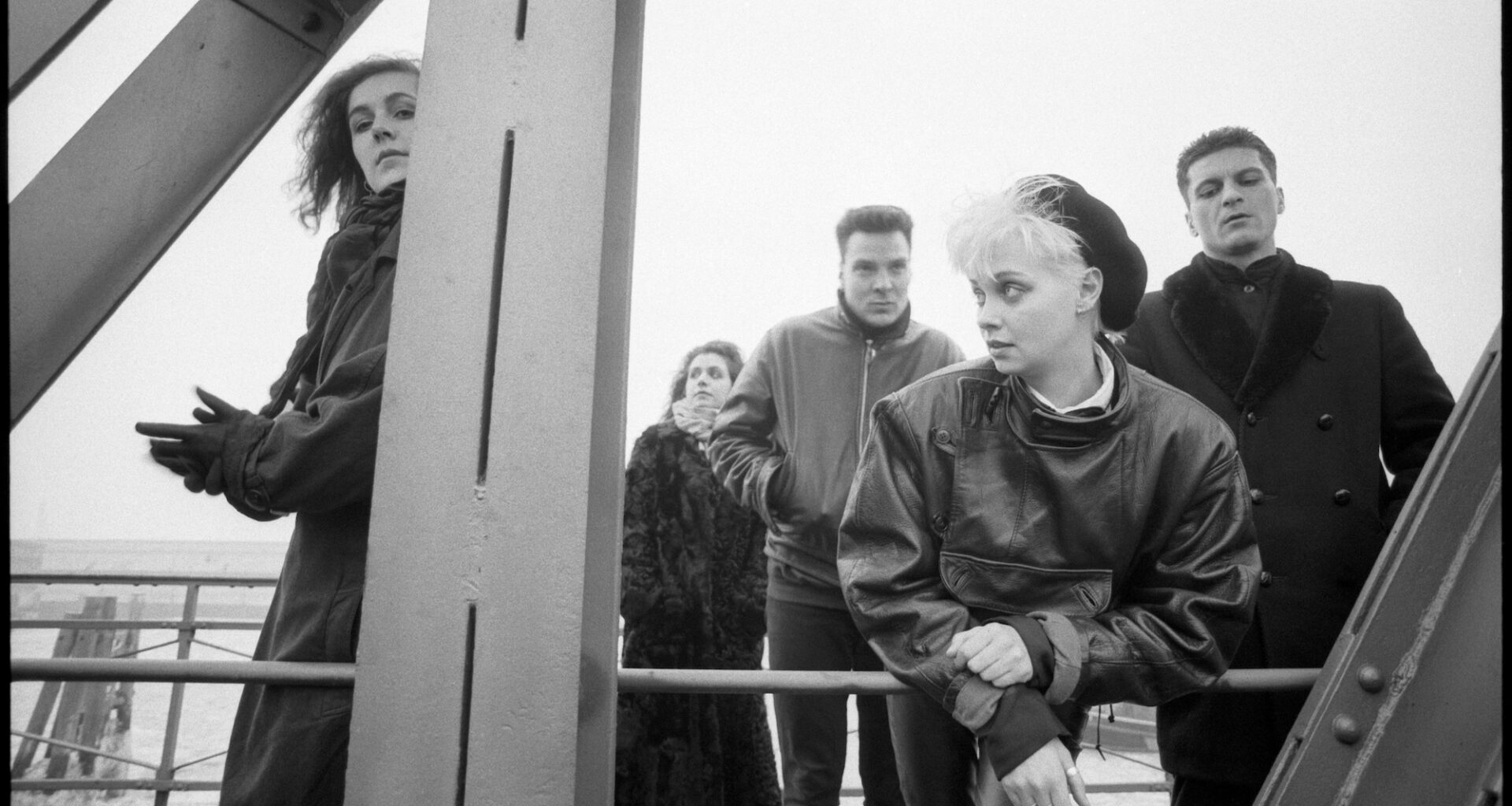 Ein Schwarz-Weiß Foto von Xmal Deutschland in Lederjacken auf einer Stahlbrücke