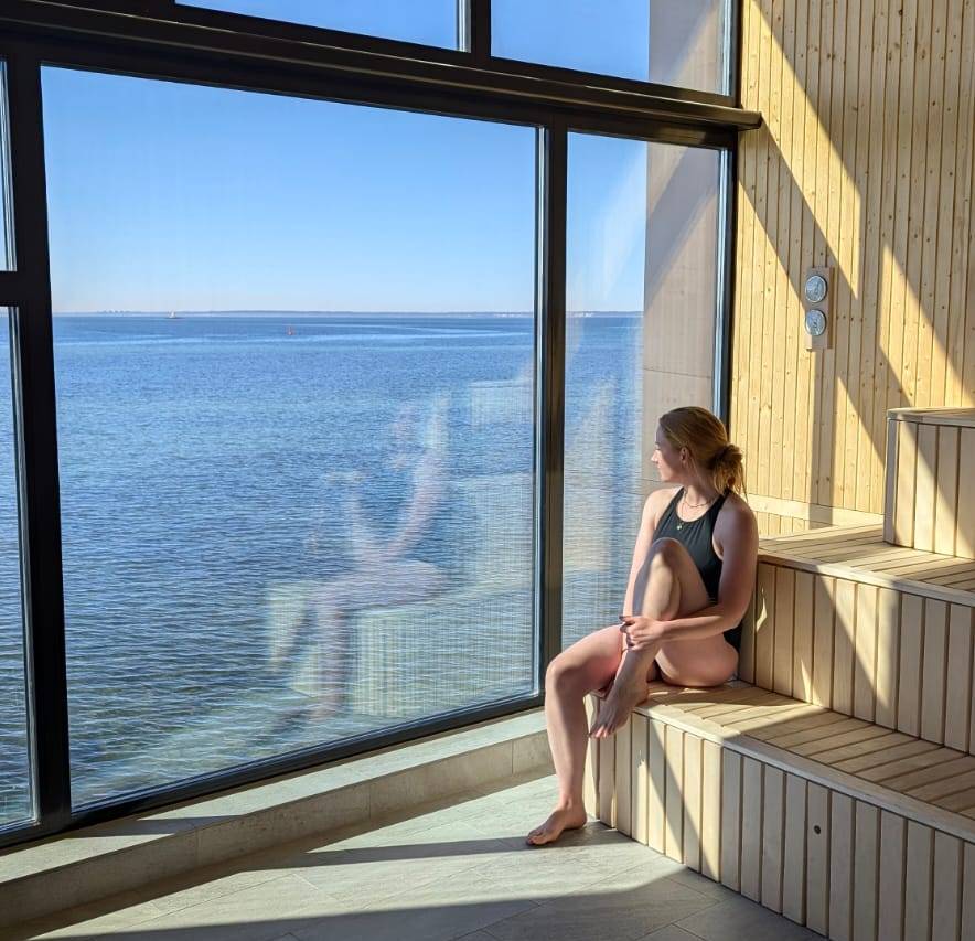 Woman sitting in a sauna overlooking the ocean.