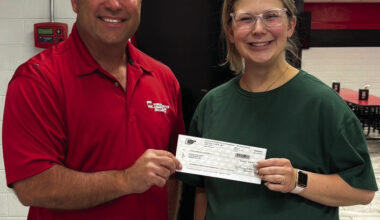 Kalley Hurt, a Carnegie High School science teacher, receives a $150 check from representative Mike Hixson