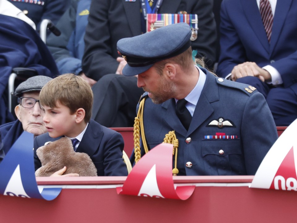 Prince Louis holding a stuffed animal while seated next to a veteran.