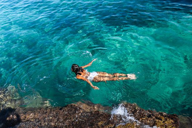 Overhead view of woman swimming beside Sardinian coast