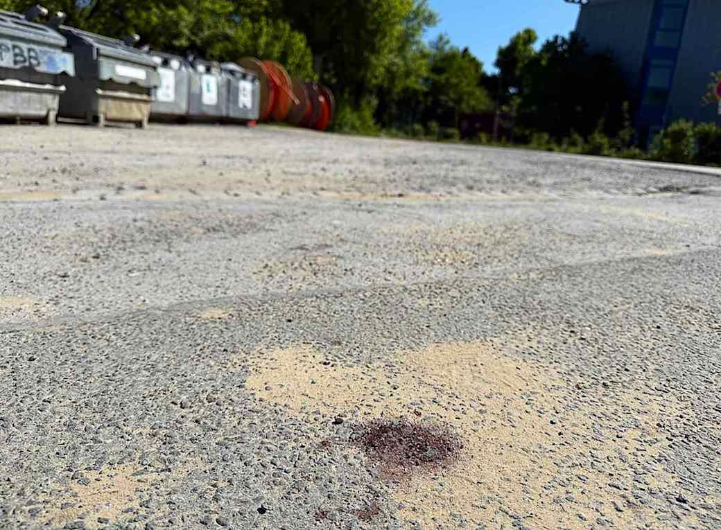 Menden Ein Blutfleck ist auf dem Asphalt am Tatort in Menden im Sauerland zu sehen. Nach dem gewaltsamen Tod eines 14-Jährigen ermittelt die Polizei. Foto: Alex Talash/dpa