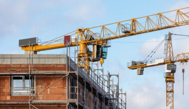 Construction site of a residential building with scaffolding and large cranes