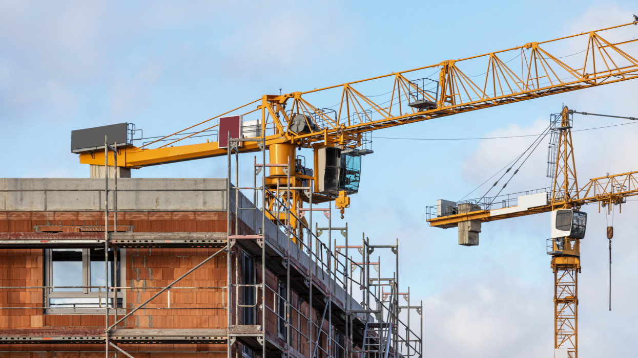 Construction site of a residential building with scaffolding and large cranes