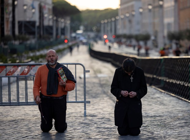 Two men recite prayers at sunrise in St. Peter's Square on May 16, 2025, before the installation of Pope Leo XIV at the Vatican. (Brian Cassella/Chicago Tribune)