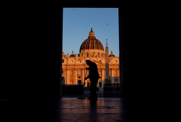 A man mops the sidewalk as the sun rises on...