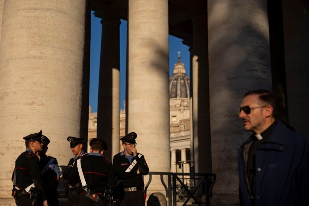 Carabinieri officers and a priest pass through St. Peter’s Square...