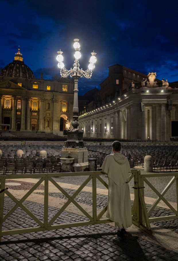A visitor takes in St. Peter’s Square as dusk falls,...