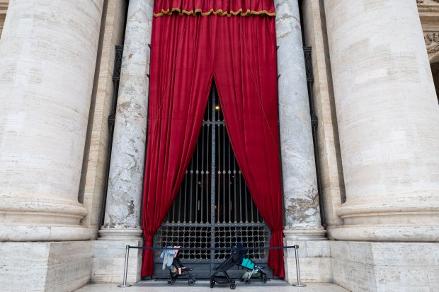 Strollers sit outside St. Peter’s Basilica on Thursday, May 15,...