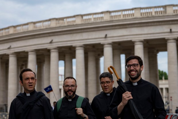 Priests walk by St. Peter’s Square on Thursday, May 15,...