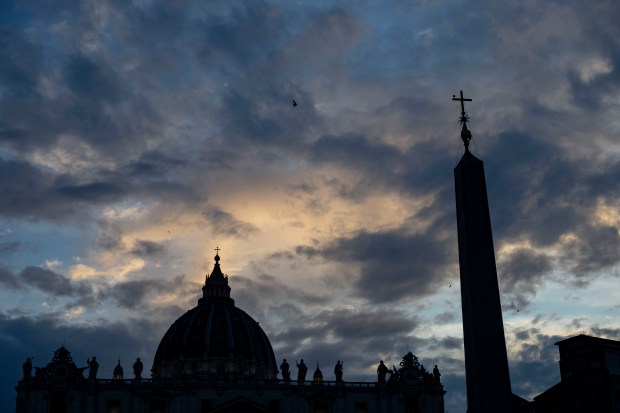 The sun sets on St. Peter’s Basilica on May 15,...