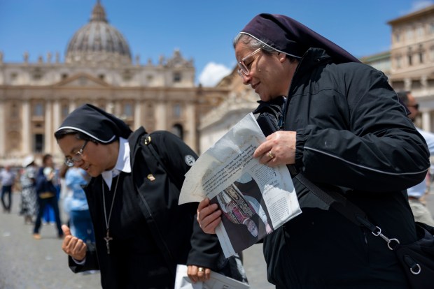 Nuns pick up newspapers featuring Pope Leo XIV after his installation Mass in St. Peter's Square on May 18, 2025, at the Vatican. (Brian Cassella/Chicago Tribune)
