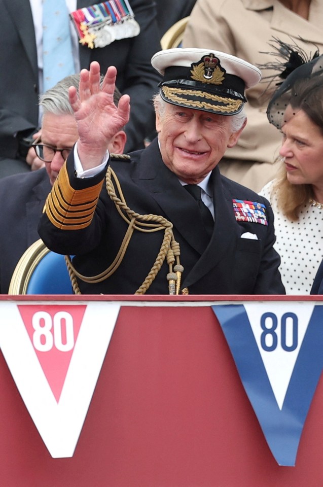 King Charles III waves at a VE Day anniversary event.