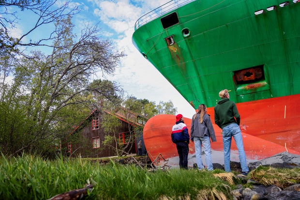 People stand near a container ship, which almost hit a house, in Trondheim, Norway, May 22, 2025. 