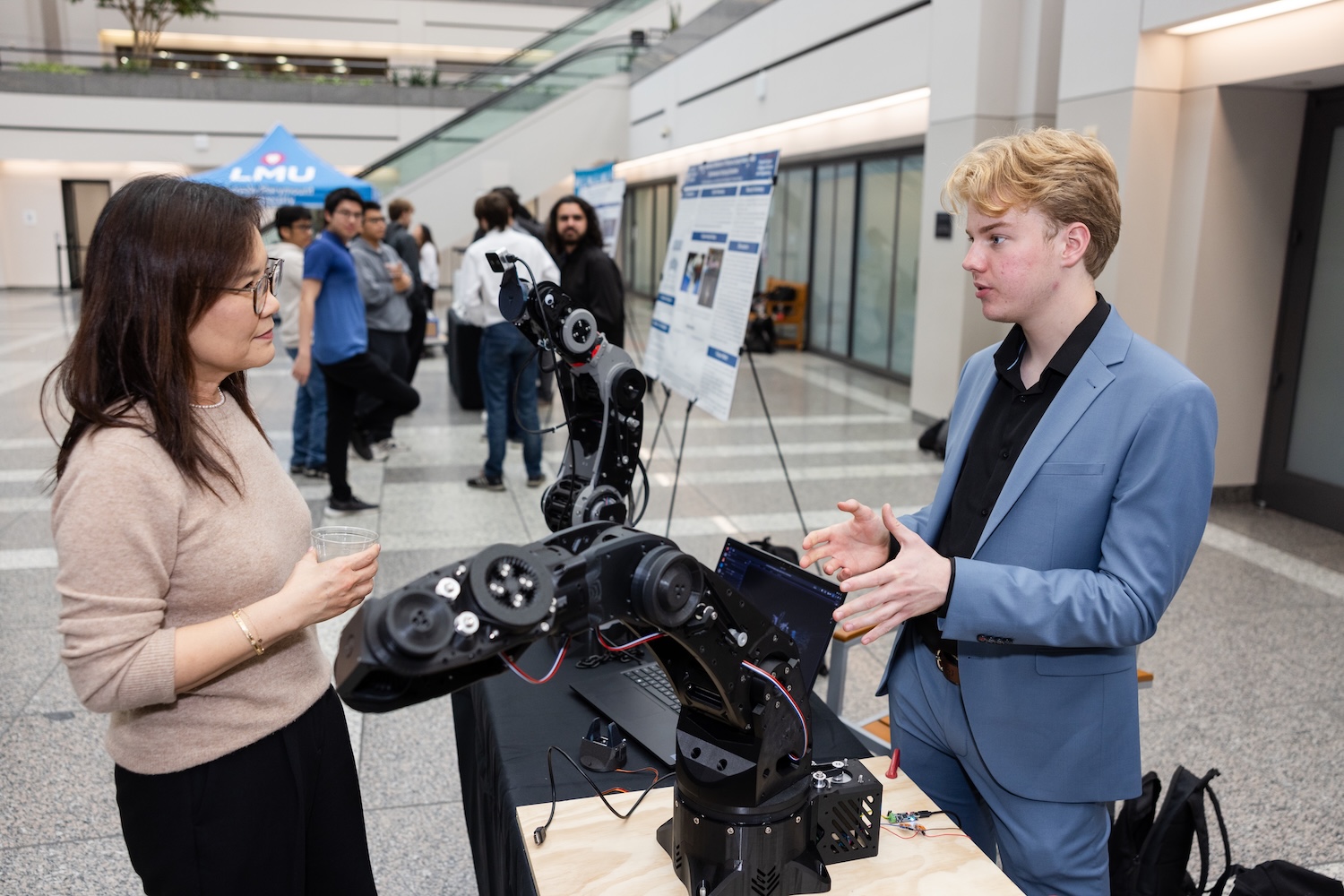 Dean Tina Choe learns about the capstone project of a student at the annual Engineering and Computer Science Design Showcase.