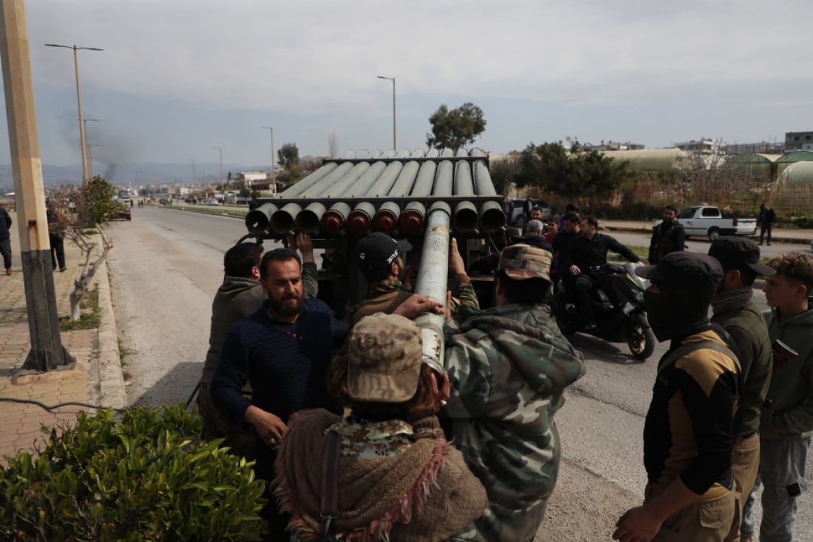 Men load a rocket launcher.