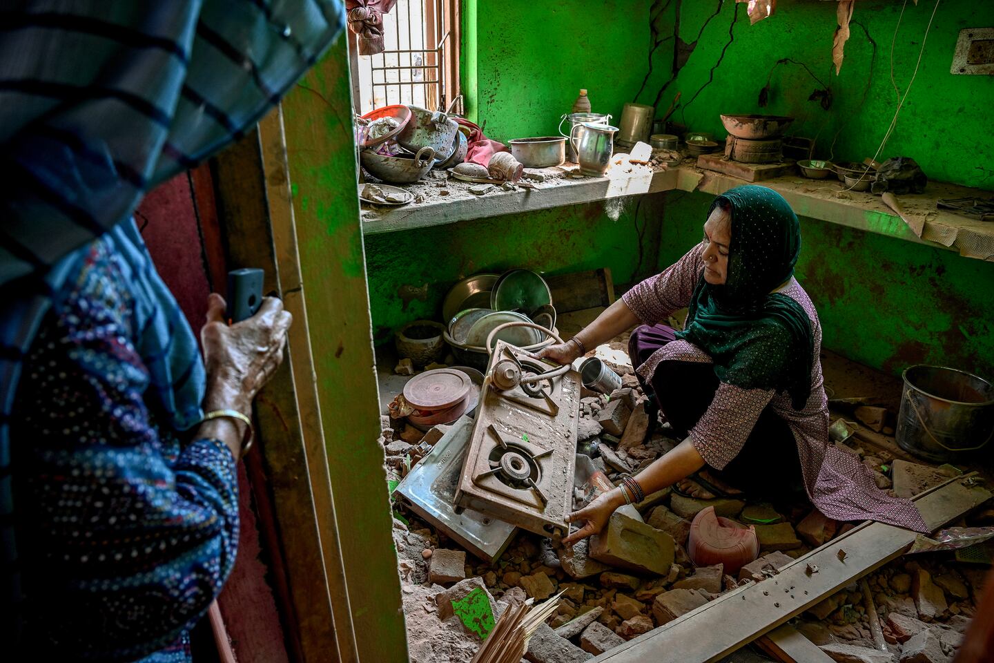 Nishu Devi searches for salvageable items in the wreckage of her home following overnight Pakistani artillery shelling in the village of Pahari Wala, in the Jammu district of the part of Kashmir controlled by India, on May 13, 2025.