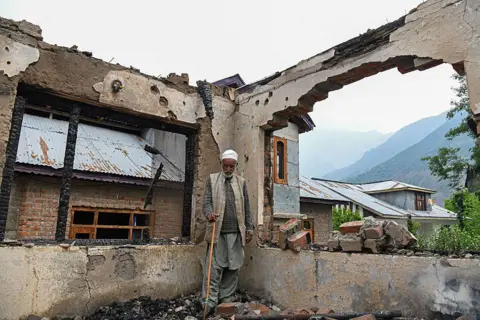 AFP A man stands inside his shell-hit home in Salamabad, Uri, near the Line of Control in Indian-administered Kashmir