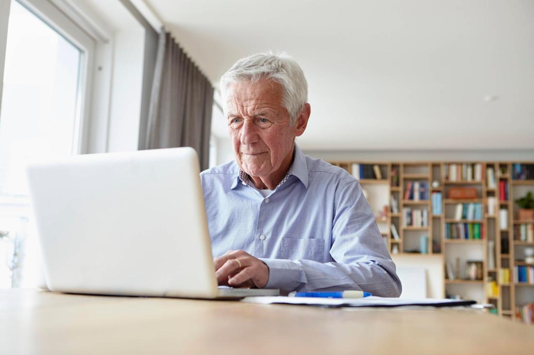 Ein alter Mann sitzt am Laptop. 